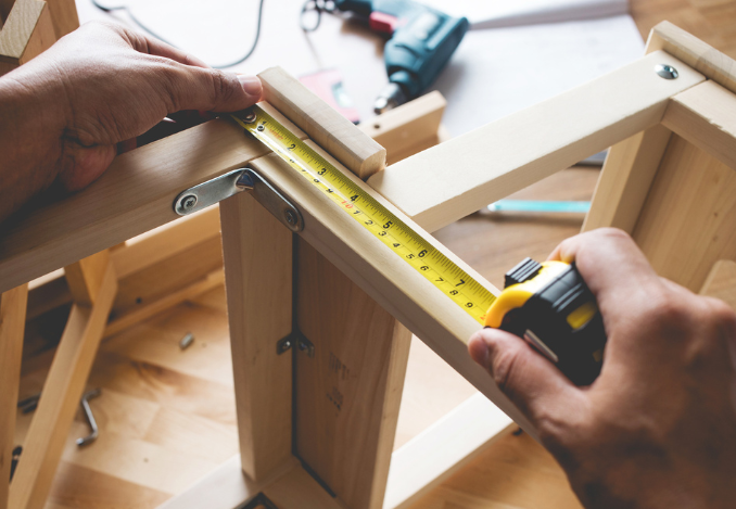 Un menuisier installateur en train de mesurer l'angle d'un élément en bois